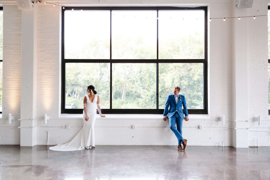 Bride and groom pose in front of massive windows of industrial-chic wedding venue Urban Daisy
