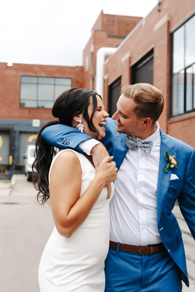 Groom wraps his arm around bride's shoulder outside Urban Daisy in downtown Minneapolis