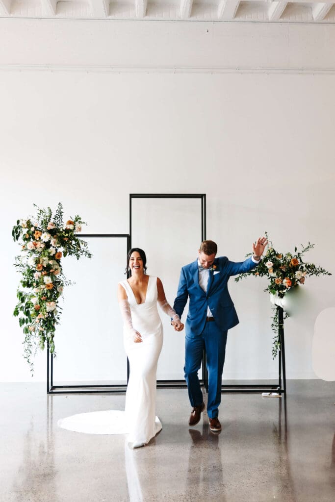 Groom raises his hands in the air as he and his bride come back down the aisle as husband and wife