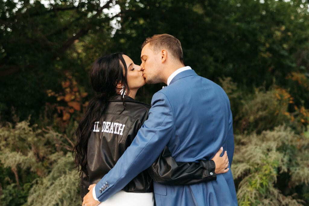 Bride wearing leather 'Til Death' jacket kisses groom