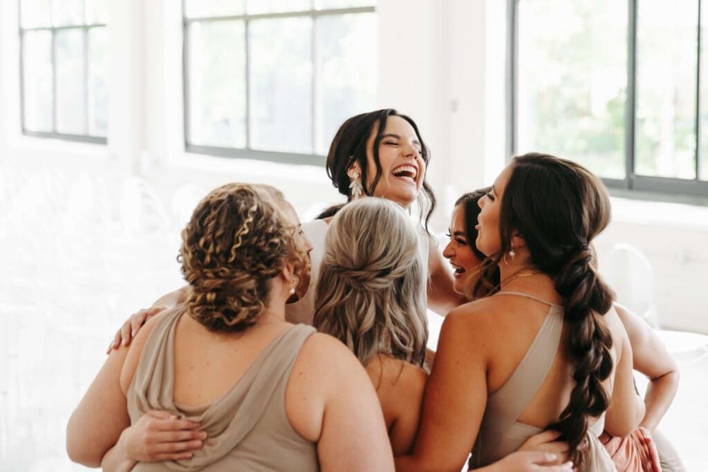 Bride and bridal party hug and laugh at Urban Daisy blank slate wedding