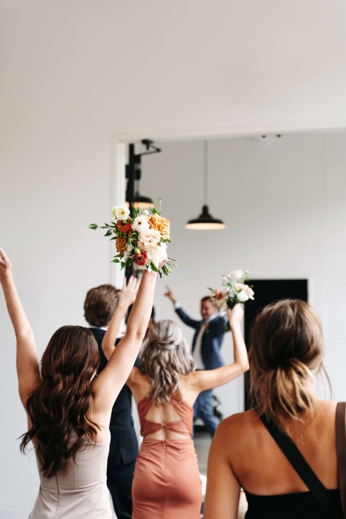 Bridal party raises their hands in celebratory motion