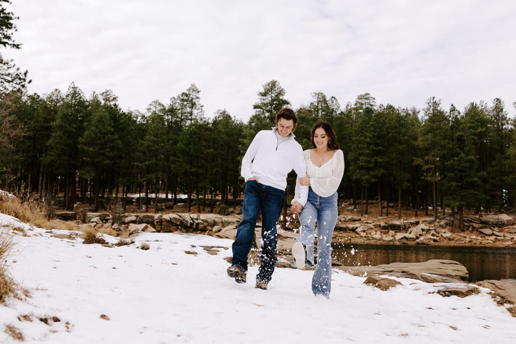 Couple kicks snow during lakeside Arizona engagement session.
