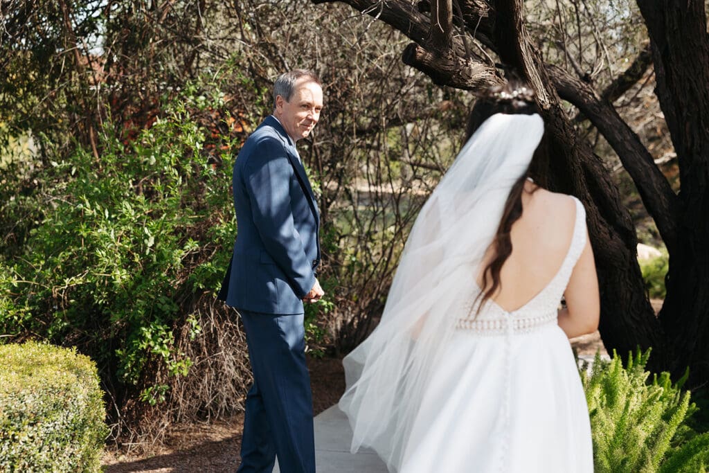 Destination wedding photographer captures father of the bride looking over his shoulder as his daughter makes her way toward him