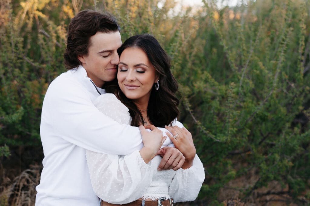 Kailey and Easton cuddling on a boulder where he proposed at the Superstition Mountains.