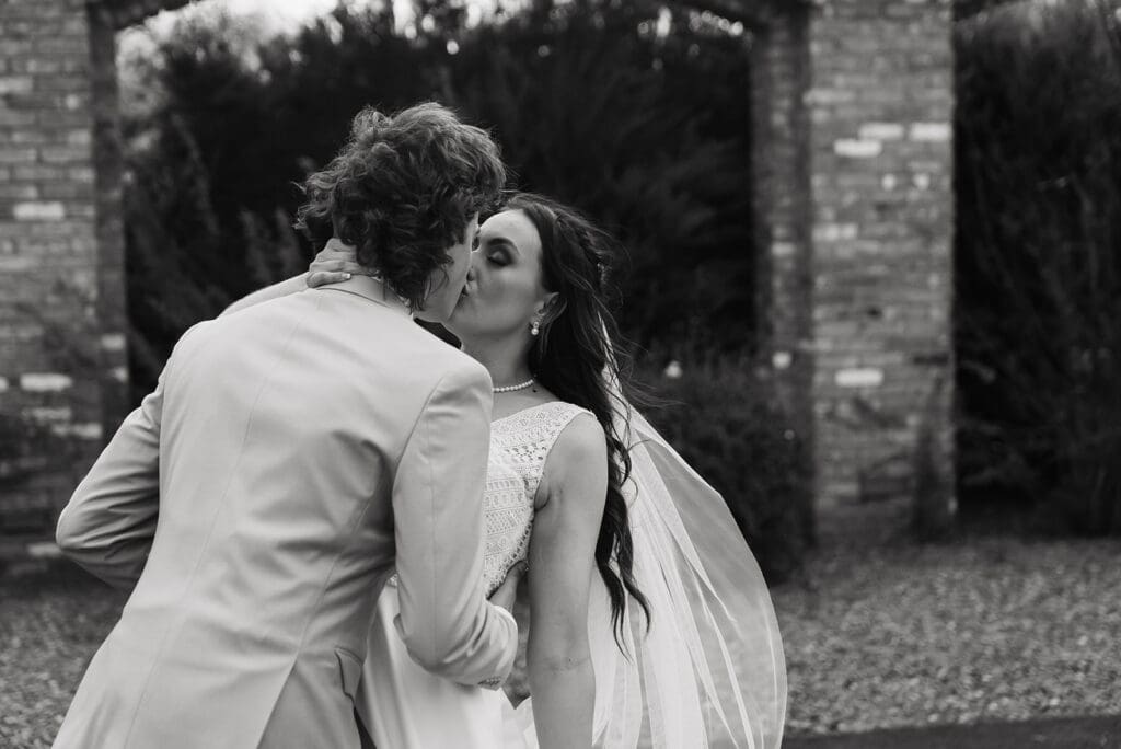 Destination wedding photographer sneak shot of groom passionately kissing his bride after they've become husband and wife