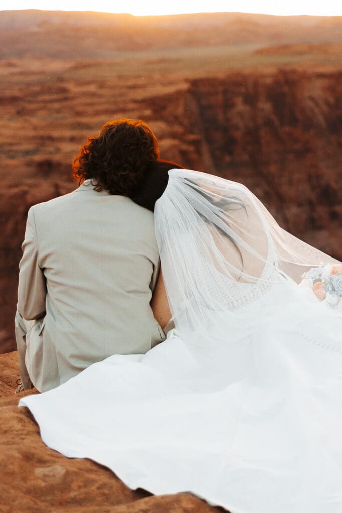 Bride rests her head on groom's shoulder in quiet moment overlooking the sun coming down over Horseshoe Bend in Arizona