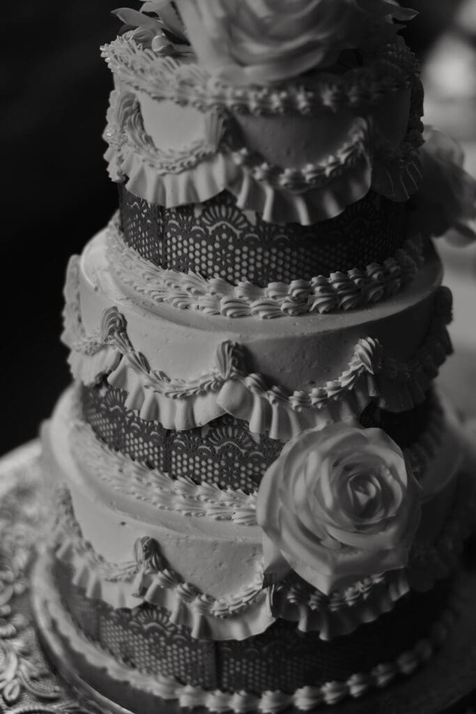 Ornate multi-tier wedding cake featuring intricate decorative details and floral accents at the reception.