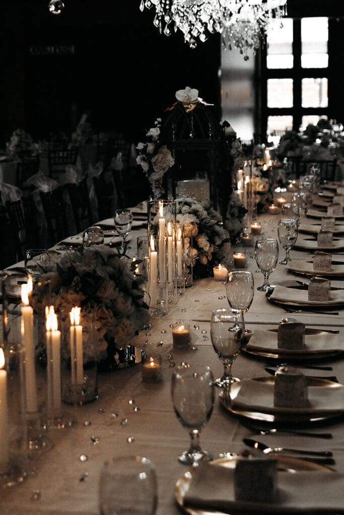 Reception tablescape illuminated by candlelight and chandeliers, showcasing reception design often documented within wedding photography and videography packages.