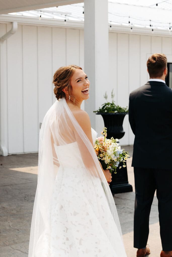 Bride smiles as she approaches her groom for their wedding first look outside a Minnesota wedding venue, Equestria West at Bavaria Downs.