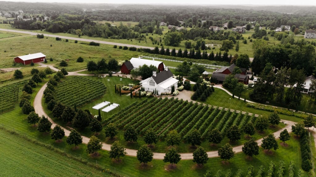 Aerial view of the vineyard rows, ceremony lawn, and sprawling grounds of Minnesota vineyard wedding venue, Redeemed Farm.