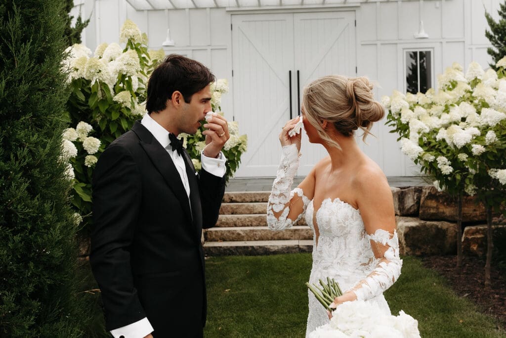 Bride and groom share an emotional moment after their first look as they wipe away happy tears together.