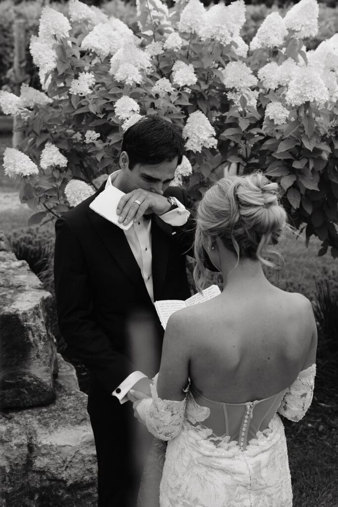 Groom wipes away tears while seeing his bride for the first time during their first look, showcasing the emotional value of wedding photography and videography packages.
