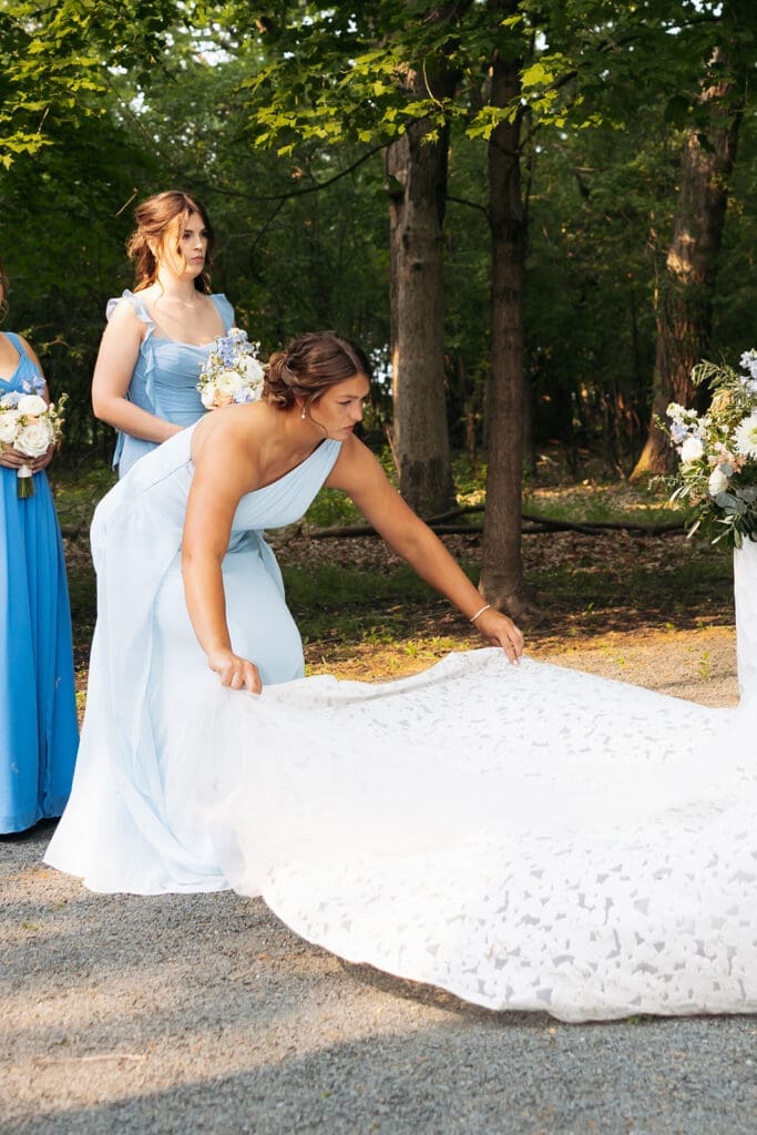 Bridesmaid straightens the bride's gown moments before the ceremony begins, one of the wedding photo tips that creates beautiful candid storytelling images.