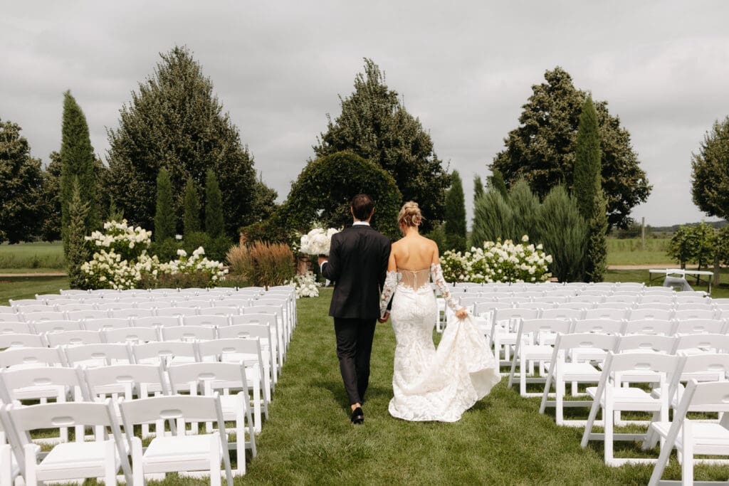 Bride and groom walking back up the aisle together through the outdoor ceremony space after exchanging vows.