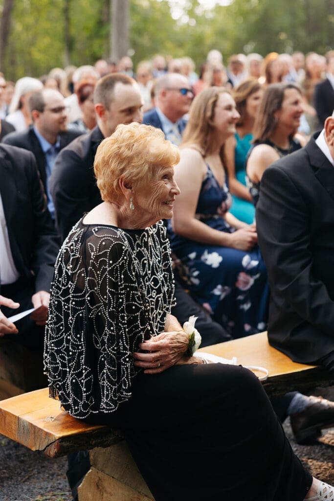Grandmother smiles during the wedding ceremony while surrounded by family and friends, highlighting the meaningful guest reactions photographers look for throughout the day.