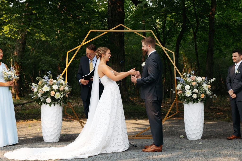 Outdoor wedding ceremony beneath a geometric arch surrounded by mature trees at one of Minnesota's most beautiful luxury wedding venues.