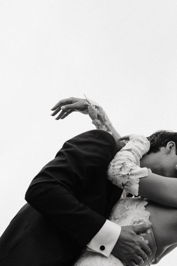 Romantic close-up portrait of newlyweds embracing beneath an open summer sky at a vineyard wedding venue in Minnesota.