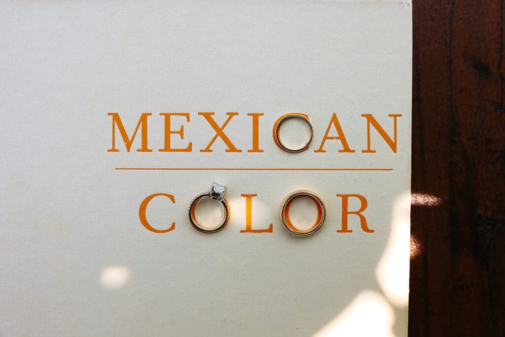 Wedding rings arranged across the cover of Mexican Color, creating a travel-inspired wedding detail photo with meaningful personal touches.