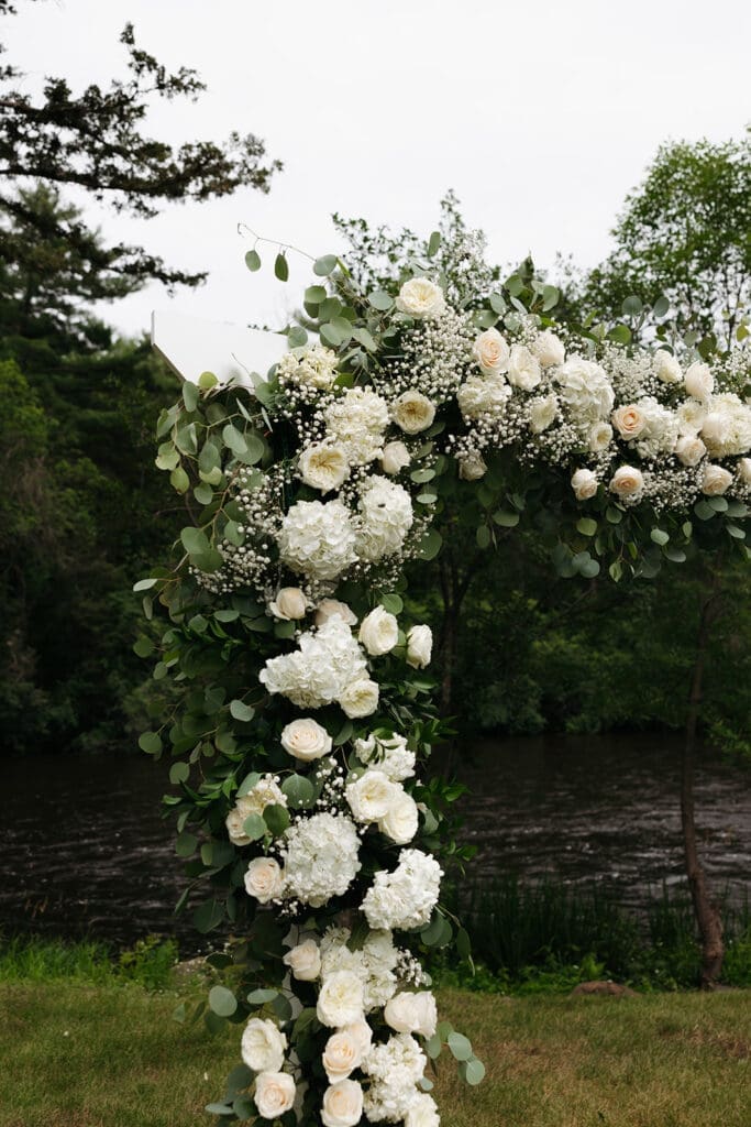 White floral ceremony arch overlooking the St. Croix River at La Pointe Events.