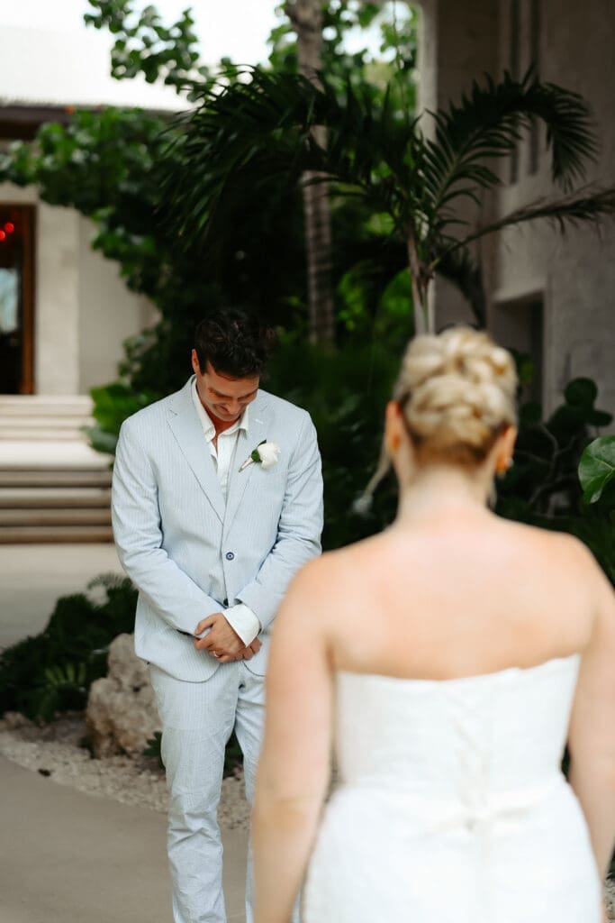 Groom looks down to fight the tears after seeing his bride during their destination wedding first look at Secrets Playa Blanca Costa Mujeres in Mexico.