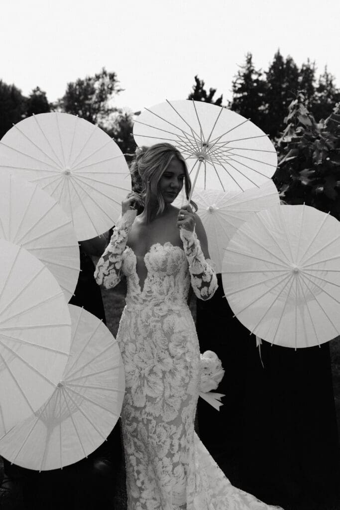 Bride posing with white parasols among the gardens at Redeemed Farm MN.