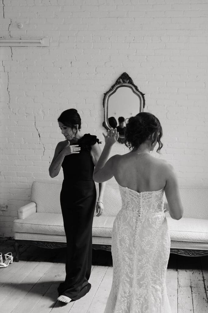 Bride and mother of the bride share a quiet moment while getting ready in a bright studio space before the wedding ceremony.