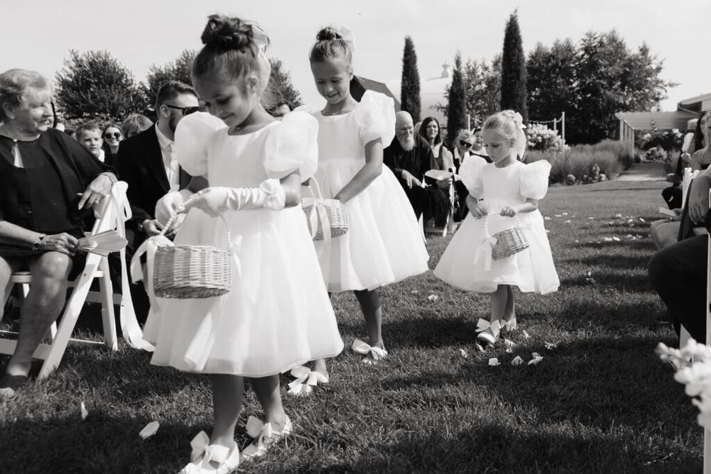 Flower girls scattering petals down the aisle during an outdoor ceremony at an estate wedding venue in Minnesota.