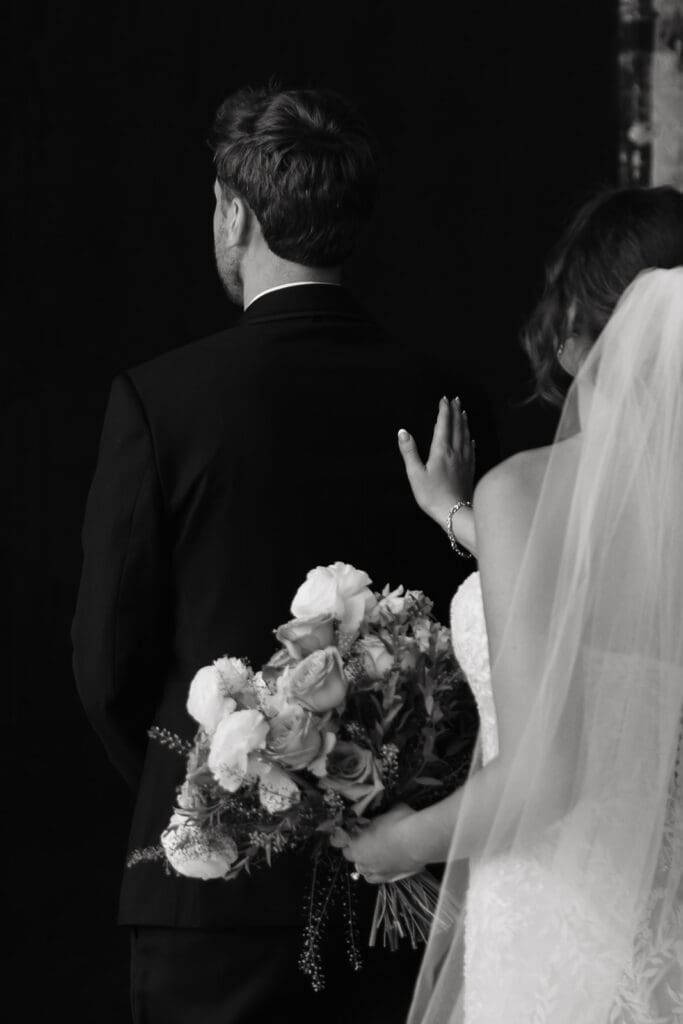 Bride taps groom on the shoulder to begin their wedding first look inside an industrial wedding venue, Northern Pacific Center in Minnesota.