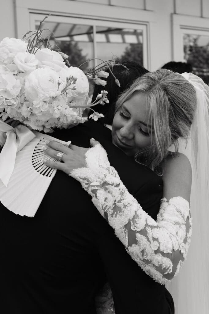 Bride hugging a loved one while holding her bouquet after the ceremony.