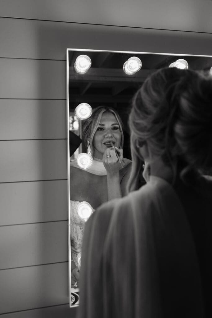 Bride applying lipstick in the mirror before the reception at her vineyard wedding venue.