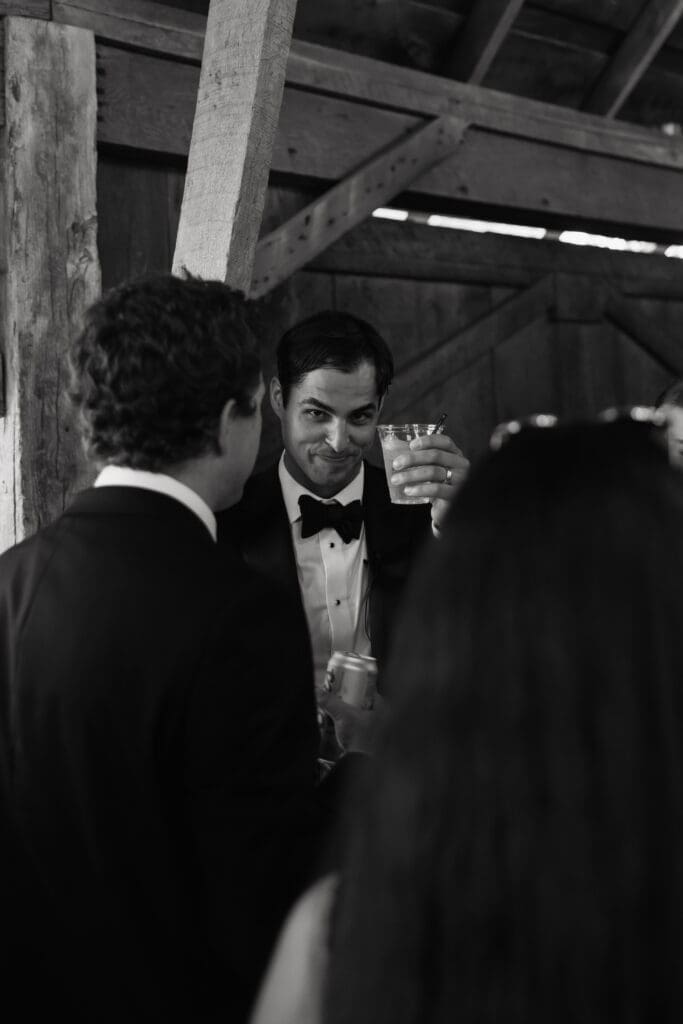 Groom raising a glass during cocktail hour inside the barn at Redeemed Farm in Scandia, Minnesota.
