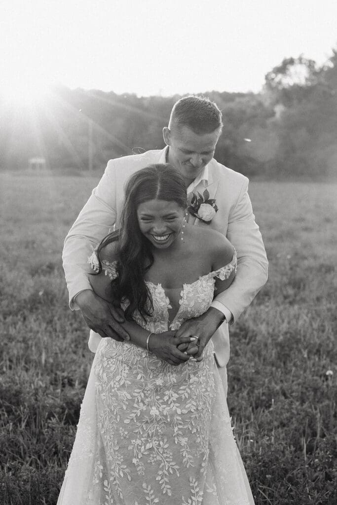 Bride and groom embracing in a sunlit field during golden hour portraits near La Pointe Events.