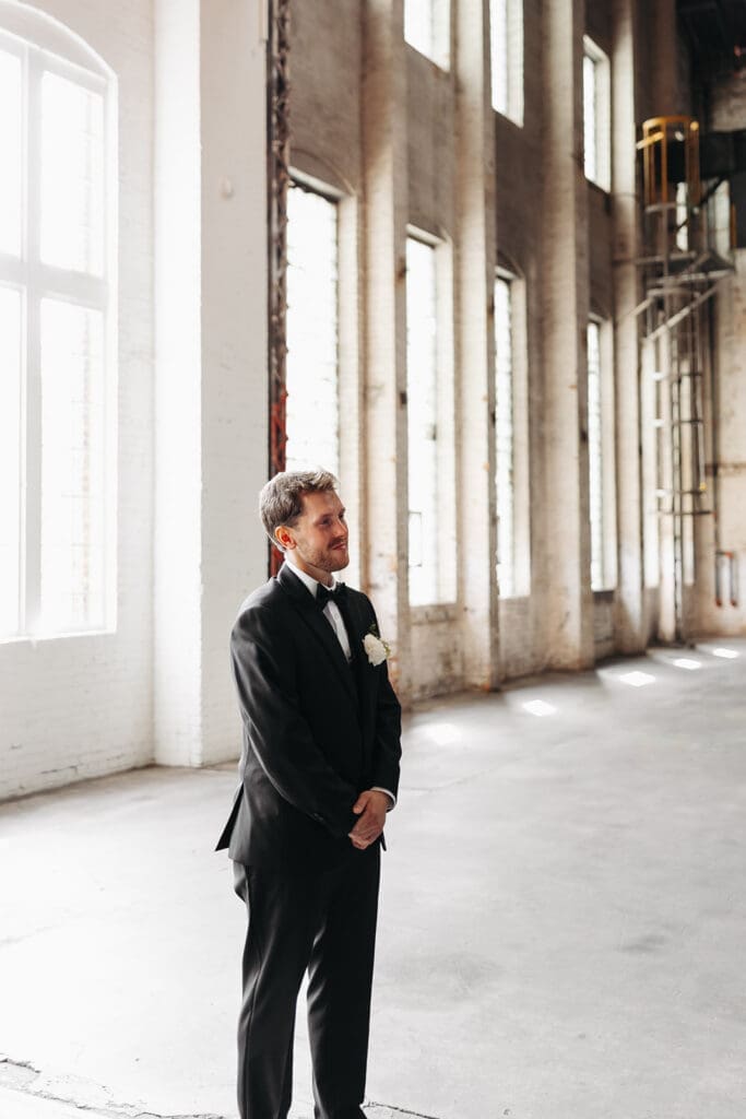 Groom waits for his bride before their wedding first look in a bright industrial venue, Northern Pacific Center.