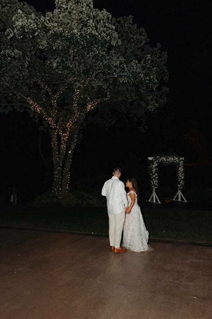 Bride and groom sharing a quiet moment beneath twinkle lights after sunset at La Pointe Events.