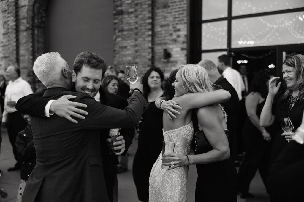 Newlyweds embrace family during cocktail hour after spending private time together before the ceremony.