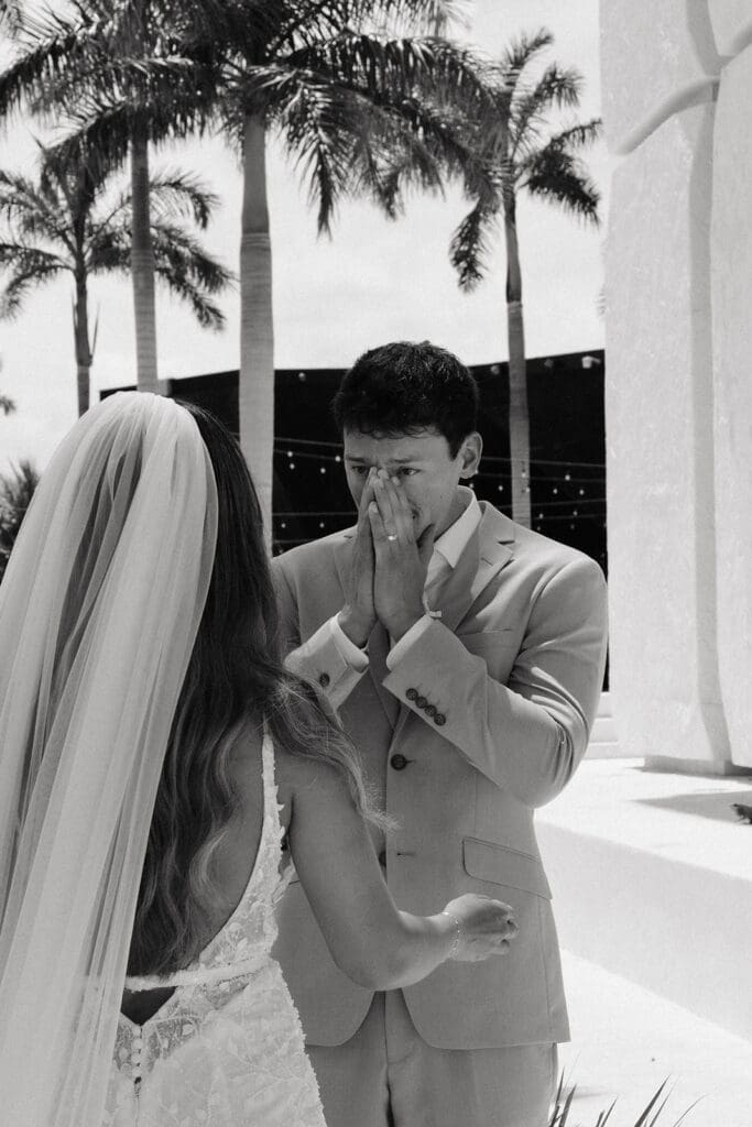 Groom reacts with happy tears during an emotional wedding first look as he sees his bride for the first time.